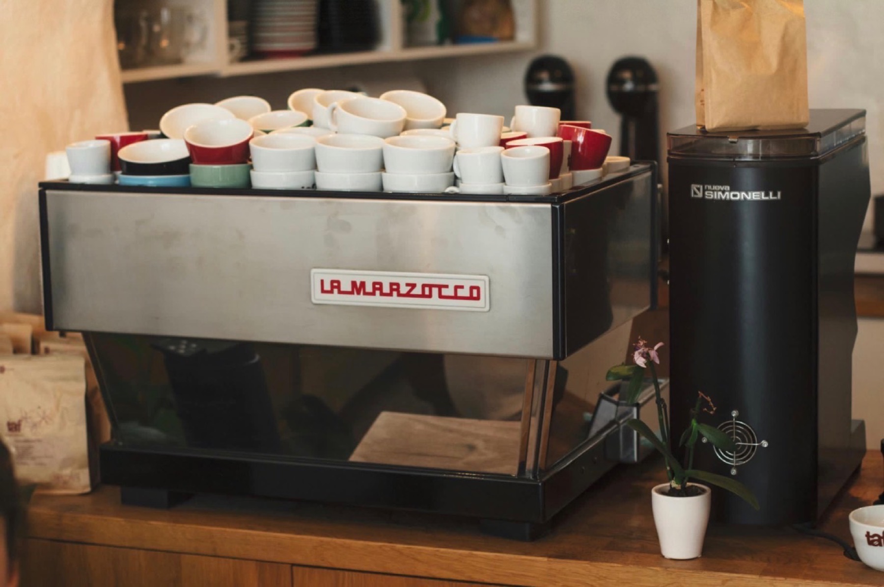 Older La Marzocco two-group espresso machine and Nuova Simonelli grinder on a café bar.